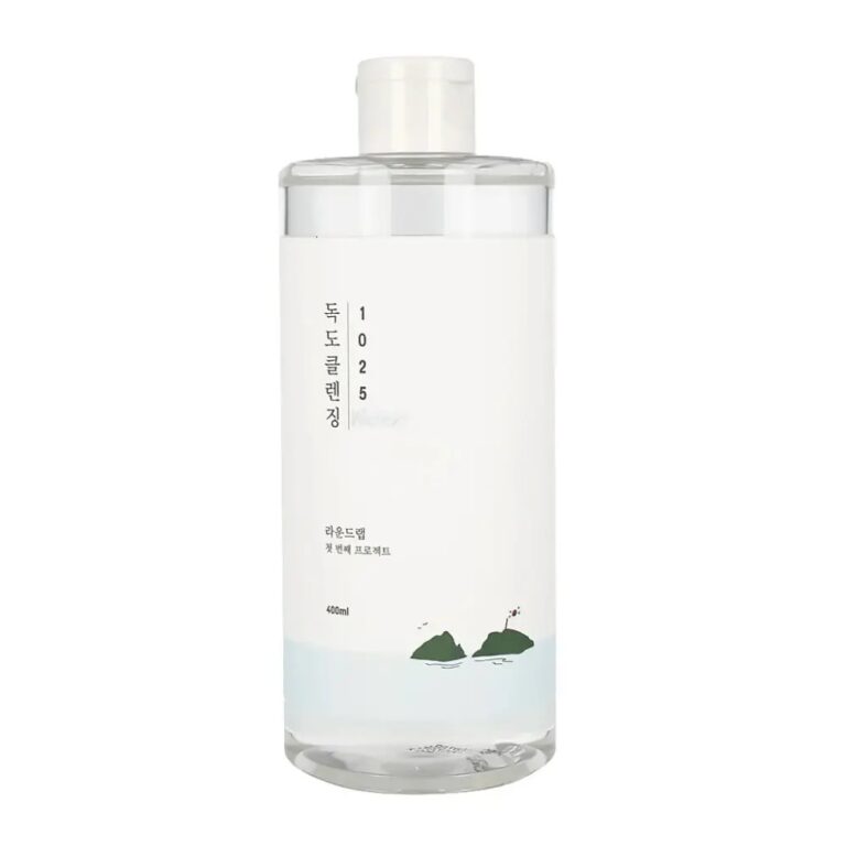 En klar flaske med en hvid etiket med koreansk tekst, minimalistisk design og en lille illustration af vand og to grønne sten indeholder Round Lab - 1025 Dokdo Cleansing Water 400 ml.
