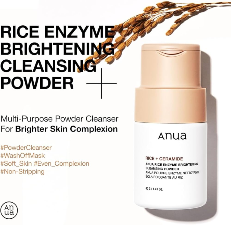 En flaske Anua - Rice Enzyme Brightening Cleansing Powder 40g står oprejst ved siden af riskorn på en hvid baggrund og fremhæver dens risenzymdrevne lysnende og blide rensning for blød, jævn hudtone.