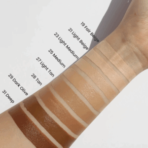 En arm viser farveprøver af Heimish - BB Mringa Ceramide SPF 30 PA++ foundation i nuancer fra 19 Fair Beige til 31 Deep, der hver især giver SPF 30-beskyttelse og ceramidpleje for et fejlfrit og næret look.