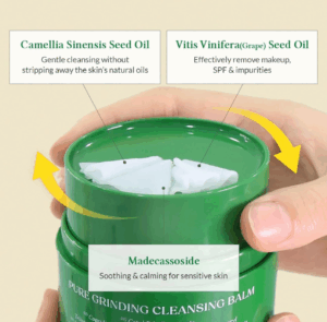 En hånd holder Dr. Althea - Pure Grinding Cleansing Balm 50 ml. Teksten fremhæver Camellia Sinensis-frøolie til skånsom rensning, Vitis Vinifera-frøolie til fjernelse af makeup og Madecassoside til at berolige sensitiv hud.
