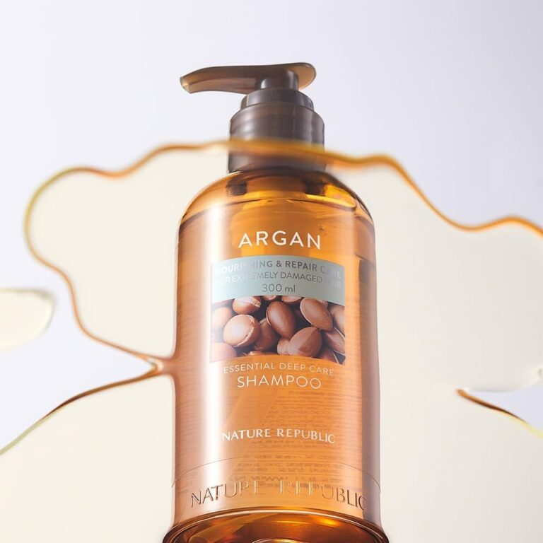 En 300 ml flaske Nature Republic - Argan Essential Deep Care Shampoo med pumpe står oprejst på en lys baggrund, omgivet af et spild af gylden væske.