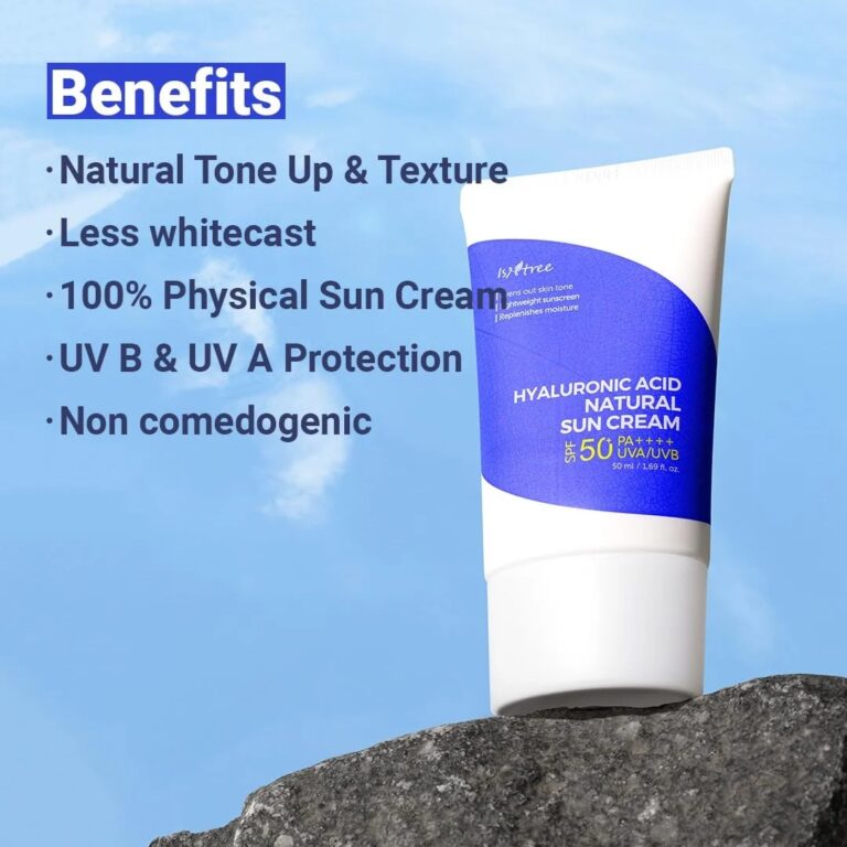 En hvid og blå tube med påskriften "Isntree - Hyaluronic Acid Natural Sun Cream SPF50+ PA++++" står på en klippe under en blå himmel. Teksten fremhæver den naturlige tone, minimal whitecast, fysisk UVA/UVB-beskyttelse og ikke-komedogene fordele.