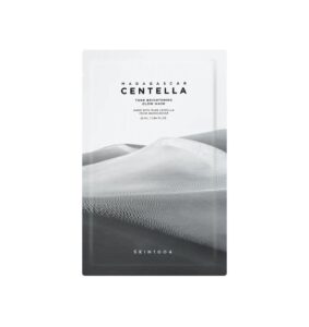 En hvid pakke mærket SKIN1004 - Madagascar Centella Tone Brightening Glow Mask har et billede af sorte og hvide sandklitter, og mærkets navn står nederst.
