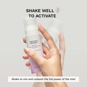 En hånd holder en Haruharu Wonder - Black Rice Probiotics Barrier NAD+ Serum Mist-flaske, med en anden sløret flaske i baggrunden. Teksten lyder: Ryst godt for at aktivere og frigøre mistens fulde kraft.
