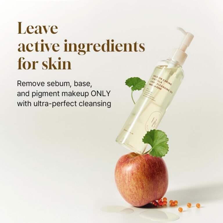 En flaske HEVEBLUE - Salmon Caring Centella Light Cleansing Oil med pumpe hviler vinklet på et rødt æble sammen med et grønt blad, små orange kapsler og dråber. Teksten fremhæver den blide, men effektive fjernelse af makeup.