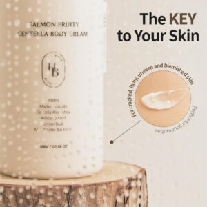 En beige flaske med HEVEBLUE - Salmon Fruity Centella Body Cream hviler på en træoverflade. Ved siden af viser et nærbillede cremen på huden og fremhæver dens fordele for revnet og ujævn hud med teksten "The KEY to Your Skin".