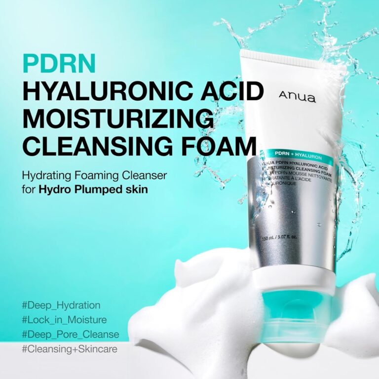 En tube Anua - PDRN Hyaluronic Acid Moisturizing Cleansing Foam står i hvidt skum med vandsprøjt bagved. Reklameteksten fremhæver hydrering og skånsom rensning for en fyldig hud. Hashtags vises i bunden.