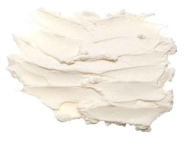 En tekstureret smørelse af hvid, cremet substans - måske glasur eller flødeskum - spredt ujævnt på en almindelig hvid baggrund, perfekt til en ingrediensleksikon-post.