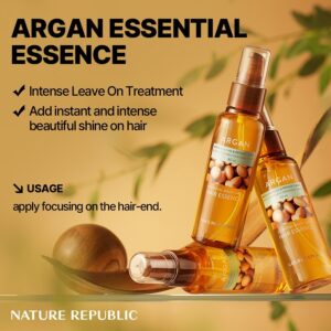 Tre flasker Nature Republic - Argan Essential Moisture Hair Oil står på en gylden baggrund. Teksten fremhæver dens leave-on-behandling, øjeblikkelige glans og hvordan man anvender olien i hårspidserne for at få det bedste resultat.