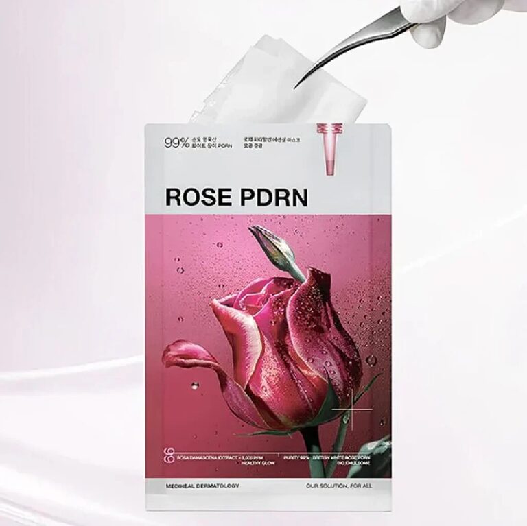 En hånd i en hvid handske holder en Mediheal Rose PDRN Essential Mask Healthy Glow-pakke med et billede af en dugfrisk rose på en lyserød baggrund.