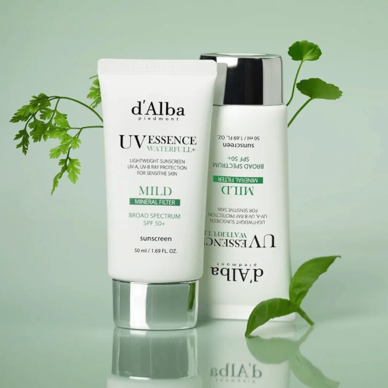 To d'Alba - Waterfull Mild Sun Cream SPF50+ PA++++ tuber, en stående og en liggende, er vist på en lysegrøn flade med friske grønne blade i baggrunden.