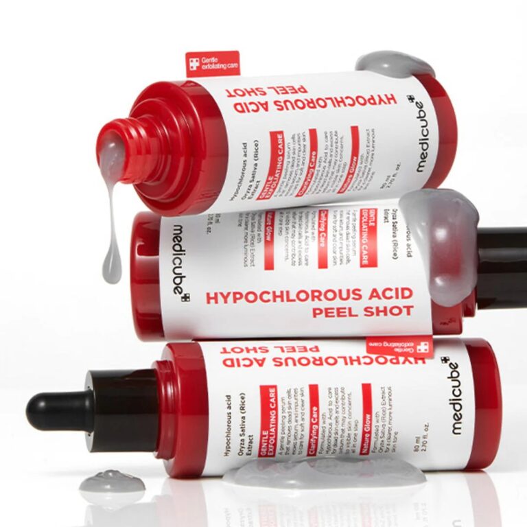 Tre Medicube - Hypochlorous Acid Peel Shot-flasker i rød og hvid er anbragt vandret med grå væske, der drypper og samler sig omkring dem på en hvid baggrund.
